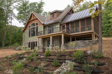 Modelo de fachada de casa verde de estilo americano grande de tres plantas con revestimiento de madera y tejado a dos aguas