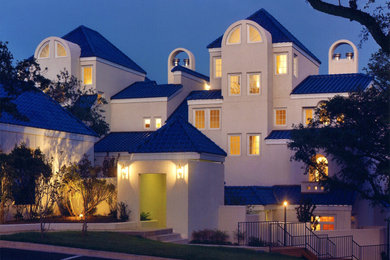 Huge tuscan white three-story stucco apartment exterior photo in Austin with a hip roof, a tile roof and a blue roof