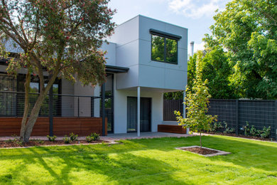 Cette image montre une façade de maison grise design de taille moyenne et à un étage avec un revêtement mixte, un toit plat et un toit en métal.