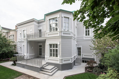 Ejemplo de fachada de casa gris clásica de tamaño medio de dos plantas con revestimiento de estuco y tejado de metal