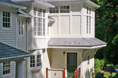 Cette image montre une façade de maison blanche traditionnelle en panneau de béton fibré de taille moyenne et à un étage avec un toit à quatre pans.