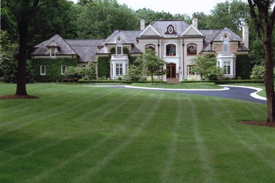 Стильный дизайн: большой, двухэтажный, серый дом в классическом стиле с облицовкой из камня и вальмовой крышей - последний тренд