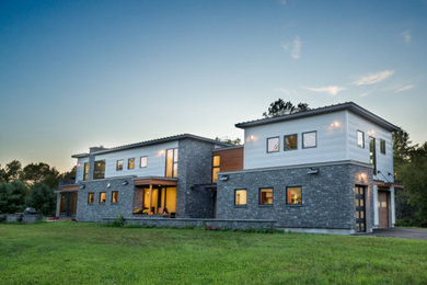 Diseño de fachada de casa blanca minimalista grande de dos plantas con revestimientos combinados y tejado de metal