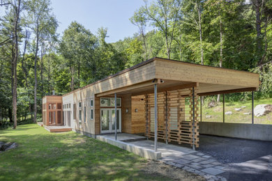 Imagen de fachada de casa rural de una planta con revestimiento de madera y tejado plano