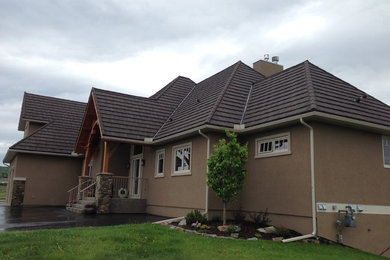 This is an example of a large and brown rustic two floor render detached house in Calgary with a hip roof and a metal roof.