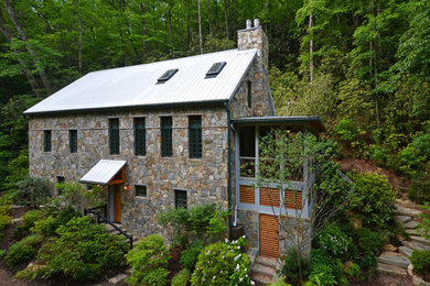 Ejemplo de fachada gris rural de tamaño medio de tres plantas con revestimiento de piedra y tejado a dos aguas