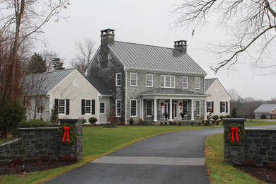 Example of a large classic gray two-story stone gable roof design in Richmond