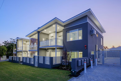Cette photo montre une façade de maison grise tendance en béton de taille moyenne et à un étage avec un toit en appentis.