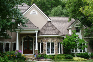 Imagen de fachada gris tradicional grande de dos plantas con revestimiento de ladrillo y tejado a dos aguas