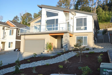 Diseño de fachada de casa beige actual de tamaño medio de dos plantas con revestimiento de vinilo y tejado de un solo tendido
