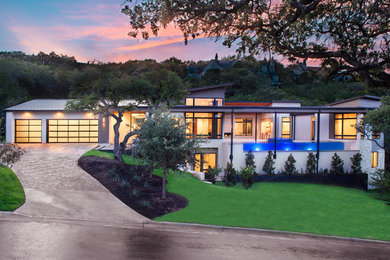 Photo of a large and beige contemporary two floor render detached house in Austin with a flat roof and a metal roof.