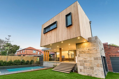 Diseño de fachada de casa beige actual de tamaño medio de dos plantas con revestimiento de madera y tejado de metal