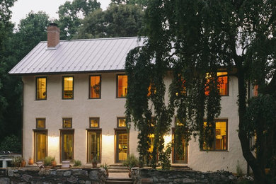 Immagine della villa beige country a due piani di medie dimensioni con rivestimento in stucco, tetto a capanna e copertura in metallo o lamiera