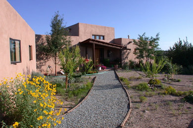 Exemple d'une grande façade de maison rose sud-ouest américain en stuc à un étage avec un toit plat et un toit mixte.