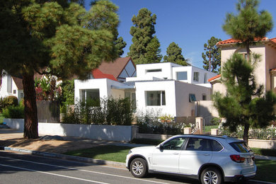 Bild på ett mellanstort funkis vitt hus, med två våningar, stuckatur och pulpettak