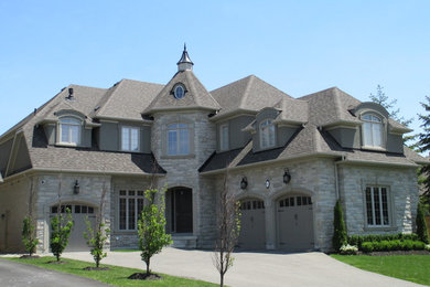 Ejemplo de fachada de casa gris clásica grande de dos plantas con revestimiento de piedra, tejado a cuatro aguas y tejado de teja de madera