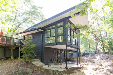 Inspiration for a large contemporary black two-story concrete fiberboard house exterior remodel in St Louis with a shed roof and a mixed material roof