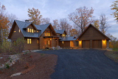 Huge mountain style brown two-story wood house exterior photo in Burlington with a clipped gable roof and a metal roof