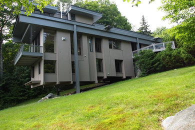 Пример оригинального дизайна: трехэтажный, серый частный загородный дом среднего размера в стиле модернизм с плоской крышей