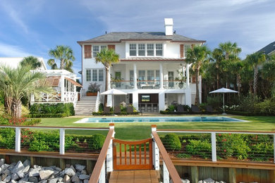 Example of a large beach style white two-story stucco exterior home design in Charleston with a hip roof
