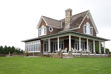 Immagine della villa grande marrone vittoriana a due piani con rivestimento in legno, tetto a capanna e copertura a scandole