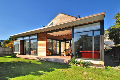 Photo of a beach style detached house in Christchurch with wood cladding.