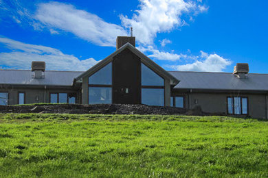 Immagine della facciata di una casa ampia beige country a un piano con rivestimento in cemento e tetto a capanna