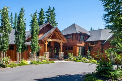 Diseño de fachada de casa marrón rural grande de dos plantas con revestimientos combinados y tejado de teja de madera