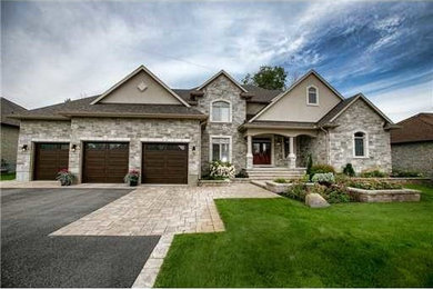Large transitional gray two-story stone exterior home idea in Ottawa with a hip roof