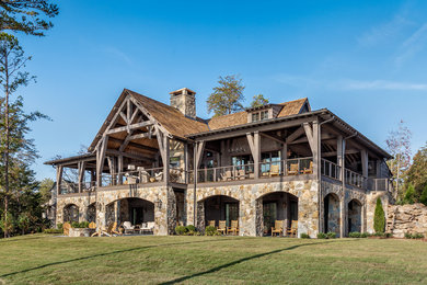 Inspiration for a huge rustic beige two-story stone gable roof remodel in Other