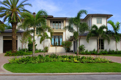 Example of a large island style white two-story stucco house exterior design in Tampa with a hip roof and a shingle roof