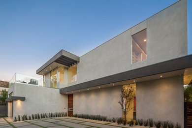 Modelo de fachada de casa gris moderna grande de dos plantas con revestimiento de estuco y tejado plano