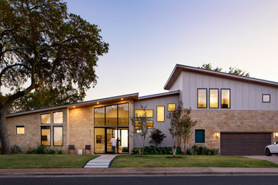 Example of a mid-century modern gray two-story mixed siding and board and batten house exterior design in Austin with a shed roof