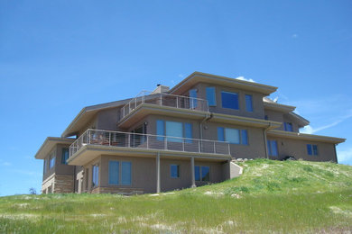Idée de décoration pour une grande façade de maison beige design en stuc à un étage avec un toit plat.
