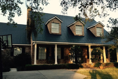 Large traditional red two-story brick house exterior idea in Orlando with a shingle roof