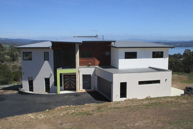 Cette photo montre une façade de maison moderne en brique à un étage avec un toit plat et un toit en métal.