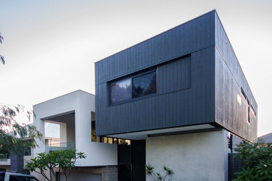 Ejemplo de fachada de casa multicolor actual a niveles con revestimiento de madera y tejado plano