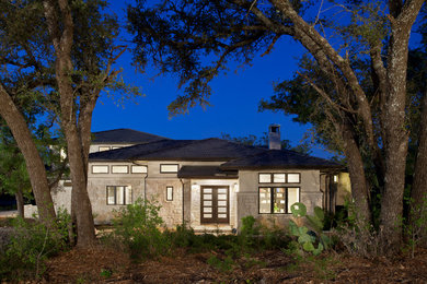 Trendy beige two-story stone exterior home photo in Austin with a hip roof