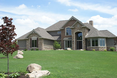 Imagen de fachada de casa gris de estilo americano grande de dos plantas con revestimientos combinados y tejado de teja de barro