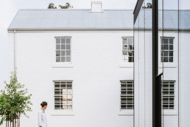 Großes, Zweistöckiges Einfamilienhaus mit Glasfassade, weißer Fassadenfarbe, Flachdach und Blechdach in Hobart