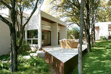 Large trendy beige two-story stucco exterior home photo in Austin with a white roof