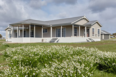 Exemple d'une façade de maison beige chic en adobe avec un toit à deux pans et un toit en métal.