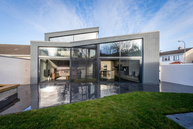 Modelo de fachada de casa gris contemporánea de dos plantas con revestimiento de metal y tejado plano