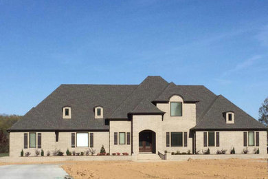 Example of a large transitional beige two-story stone exterior home design in Other with a clipped gable roof