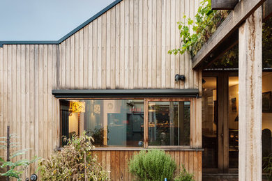Diseño de fachada de casa marrón y gris contemporánea de tamaño medio de dos plantas con revestimiento de madera, tejado a la holandesa y tejado de metal