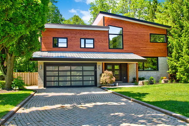 Idee per la facciata di una casa marrone moderna a piani sfalsati di medie dimensioni con rivestimento in legno e copertura in metallo o lamiera
