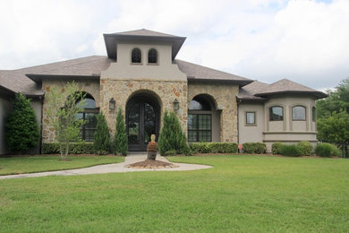 Example of a large tuscan beige one-story stucco house exterior design in Houston with a hip roof and a shingle roof