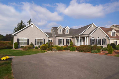 Cette photo montre une grande façade de maison grise chic de plain-pied avec un revêtement en vinyle, un toit à deux pans et un toit en shingle.