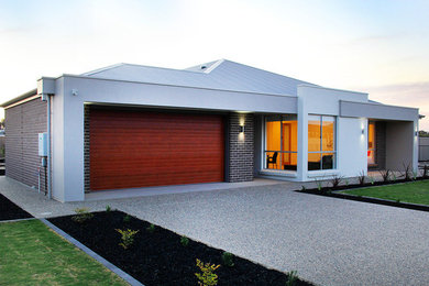 Foto de fachada de casa actual grande de una planta con revestimiento de ladrillo y tejado de metal