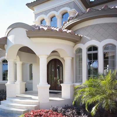 Inspiration for a large mediterranean gray two-story stucco house exterior remodel in Tampa with a hip roof and a tile roof